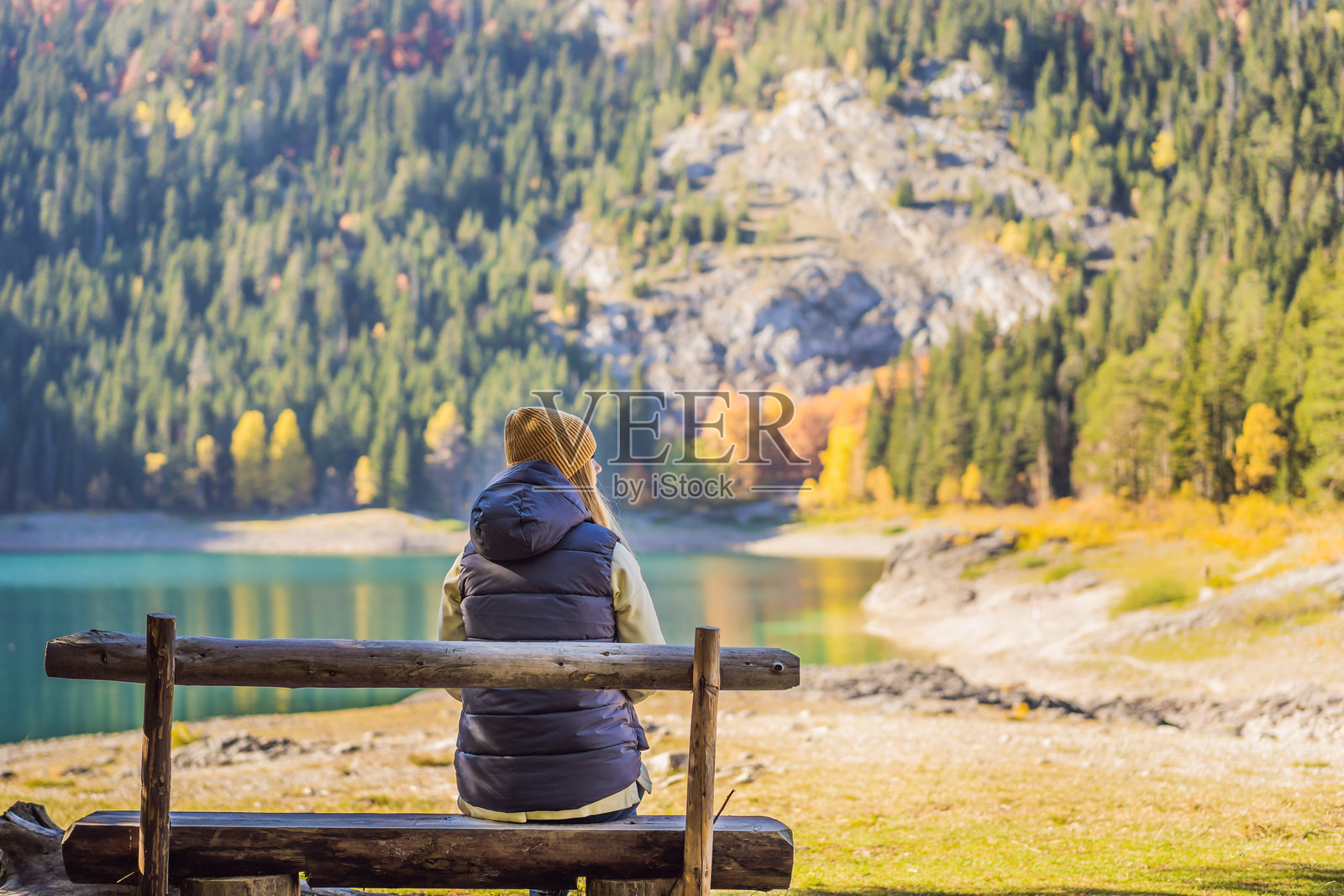 背景中有一位女性游客，前景是黑湖（Crno Jezero）全景的晨景。宁静的夏日场景，位于黑山的杜尔米托国家公园（Durmitor Nacionalni Park），扎布贾克（Zabljak）地区。自然之美的概念背景，探索黑山的旅行主题。照片摄影图片