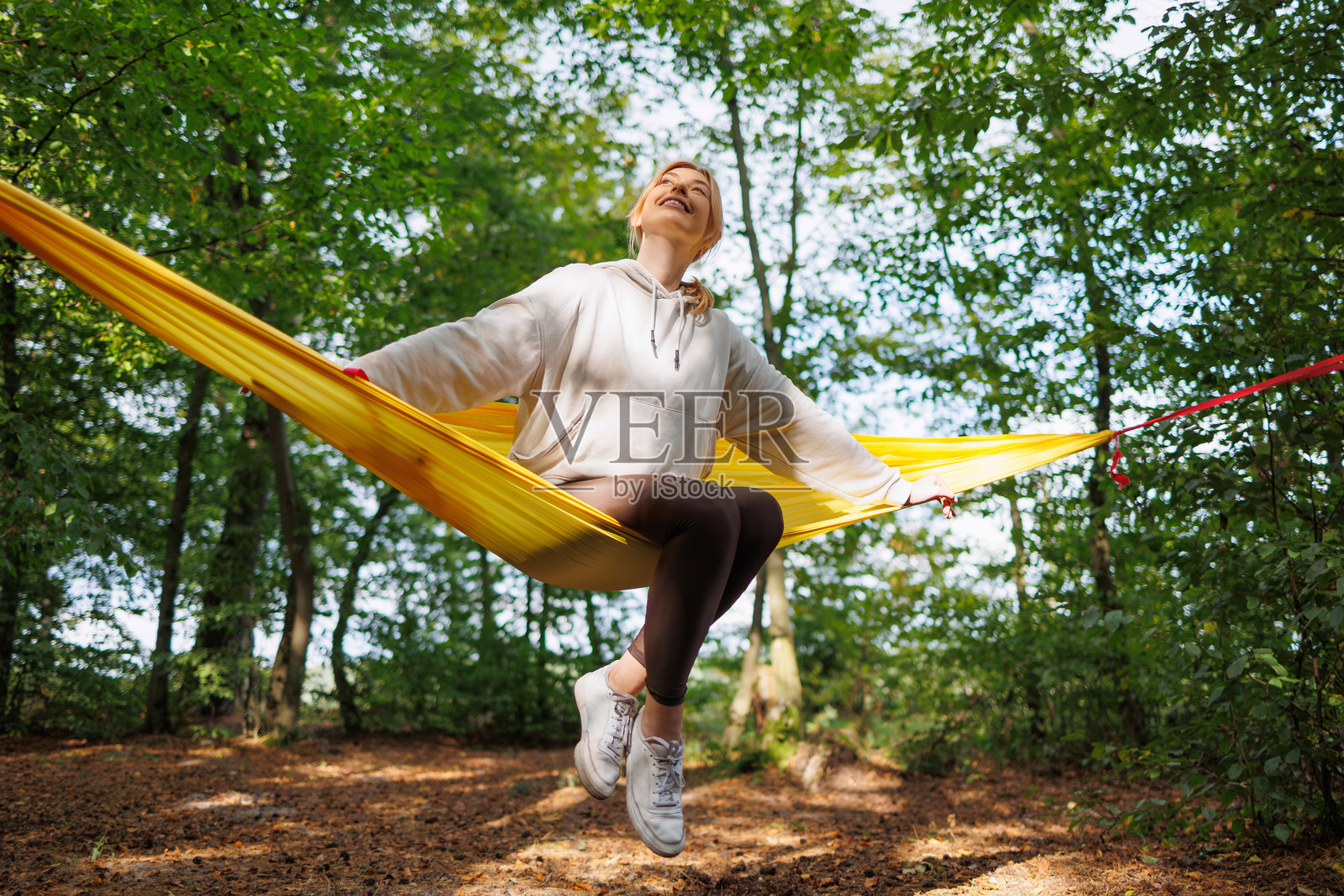 快乐的女人在森林中秋千上摇摆照片摄影图片