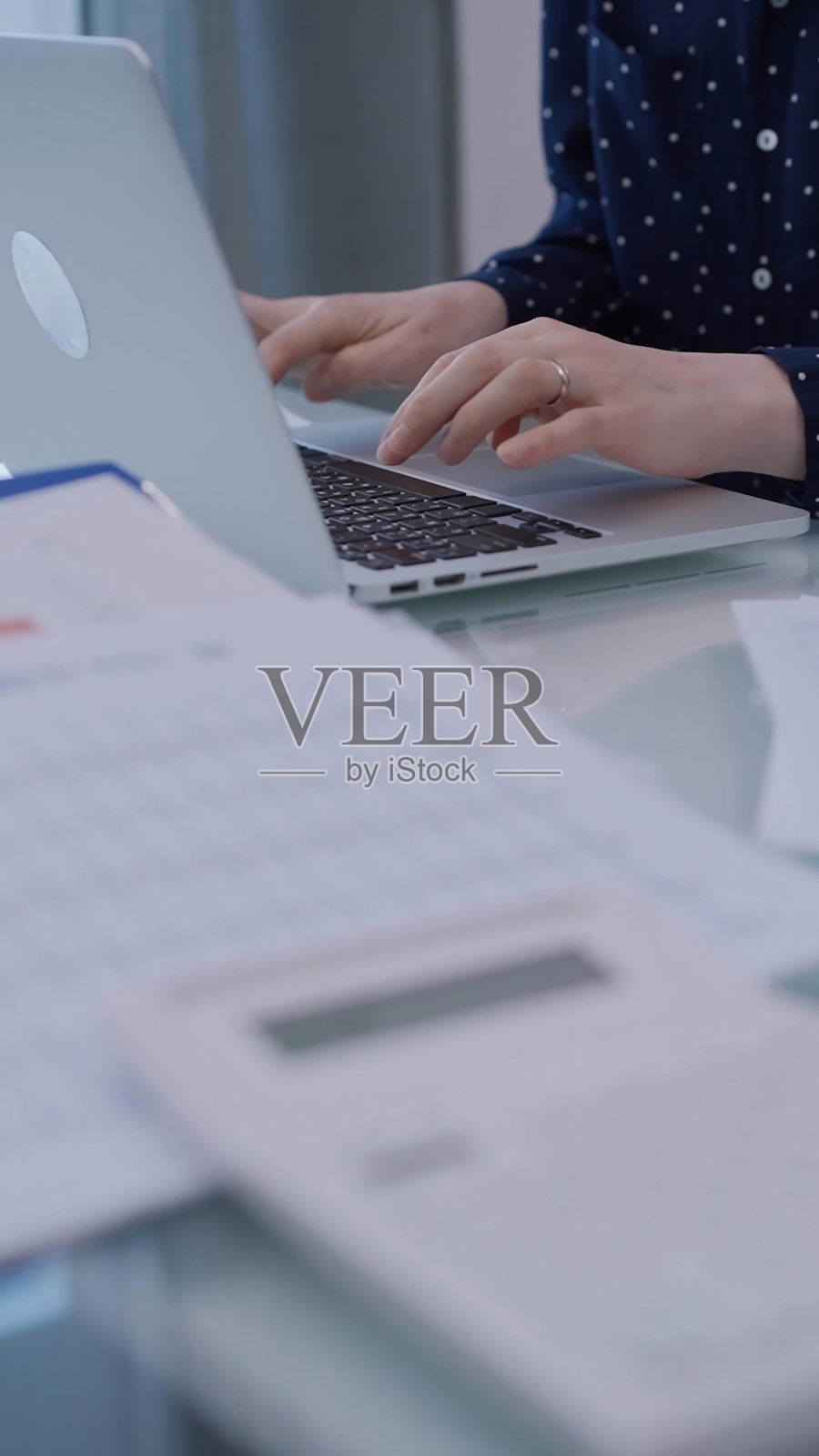 商务女性坐在办公室的玻璃桌前使用笔记本电脑，特写手部。商业概念照片摄影图片