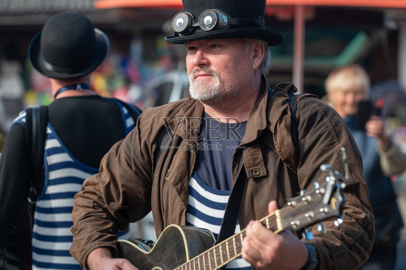 阳光明媚的日子里，街头音乐家在热闹的市场上演奏吉他照片摄影图片