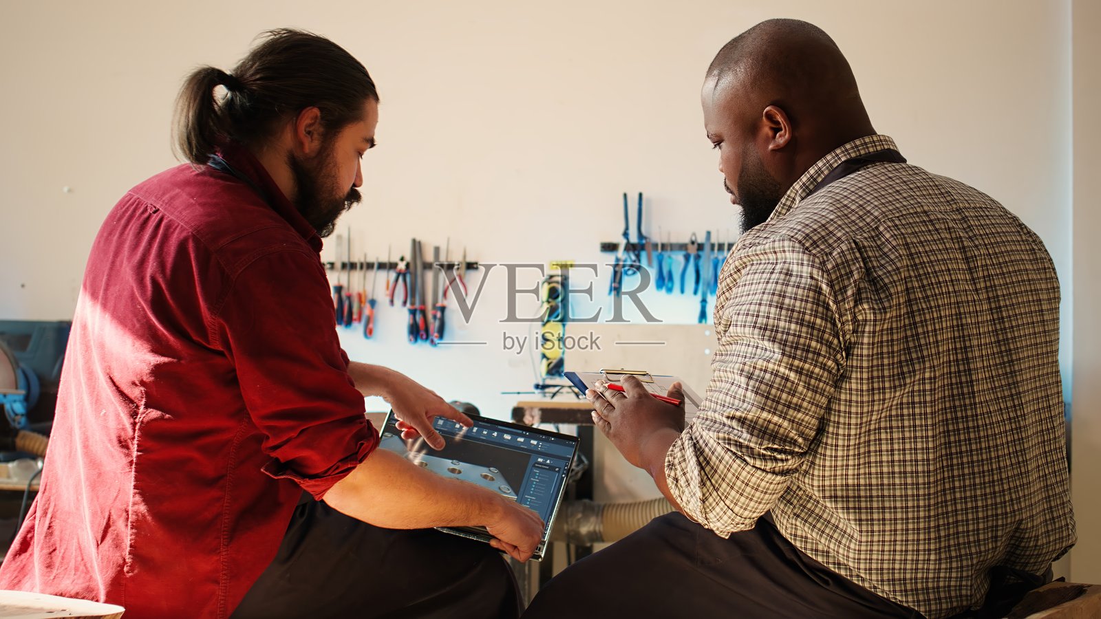 木匠在工作，使用夹板上的图纸与笔记本蓝图进行交叉检查照片摄影图片