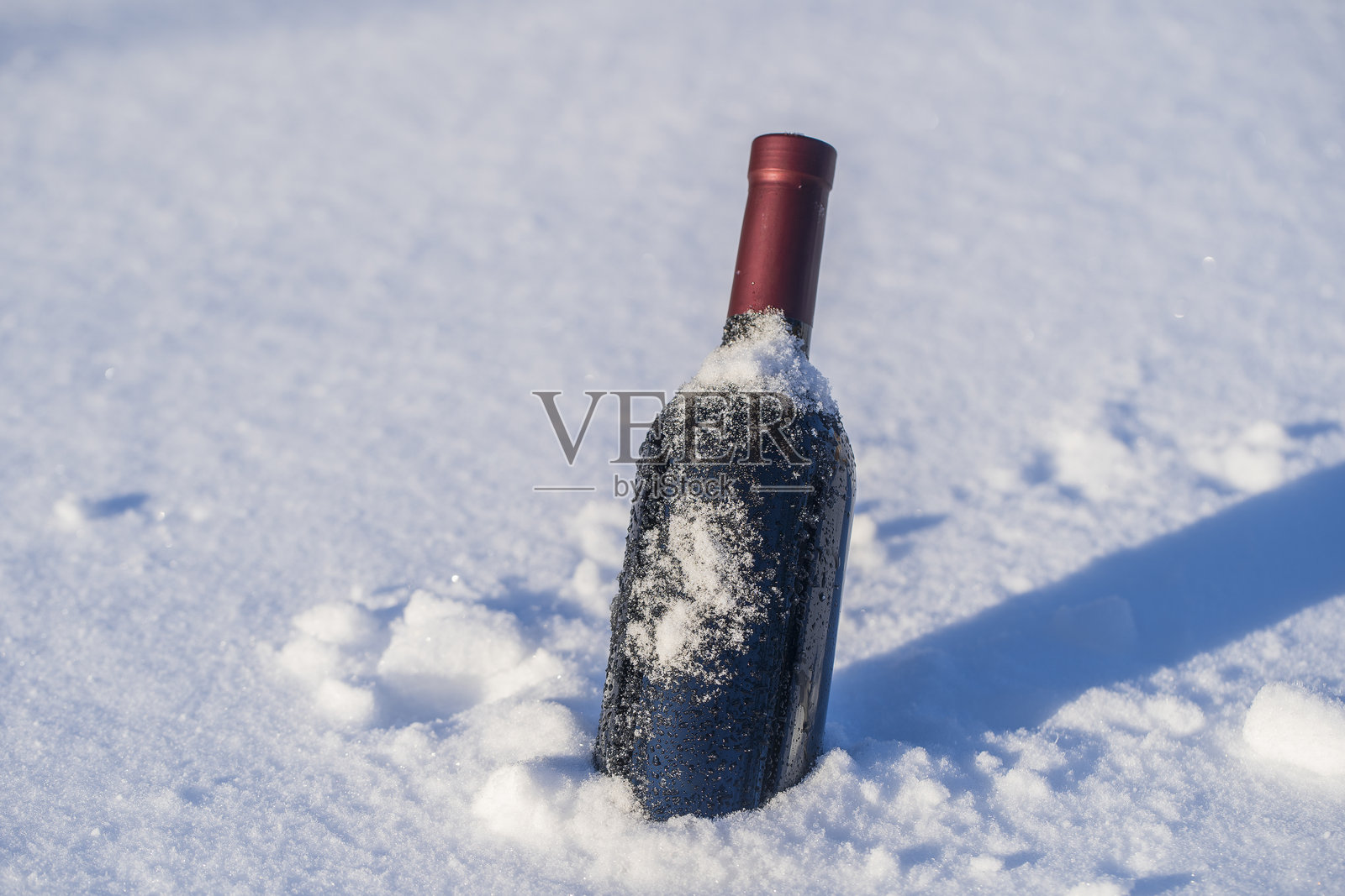 雪地和白色背景上的红酒瓶照片摄影图片