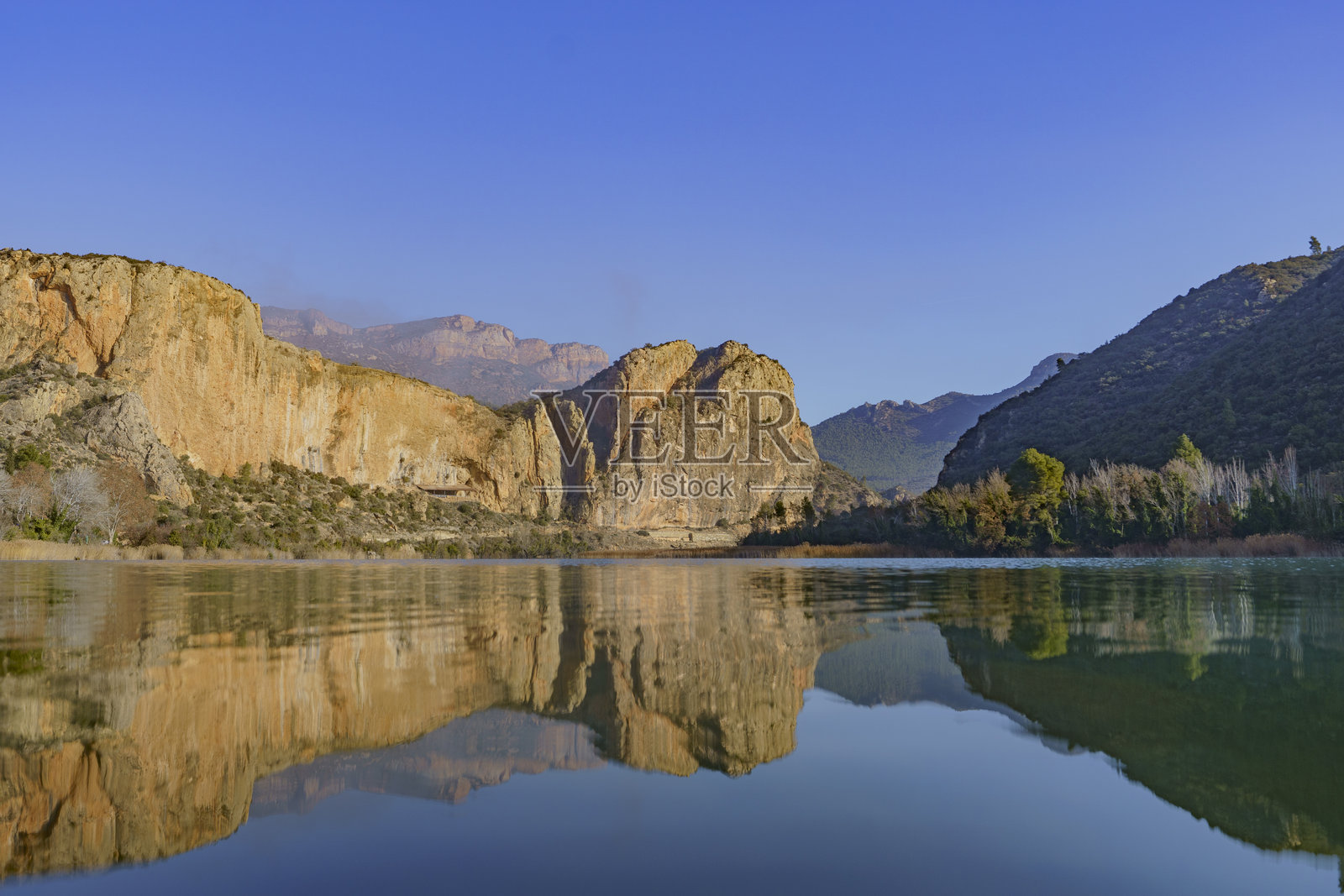 一幅宁静湖面上山脉和岩石的景观。照片摄影图片
