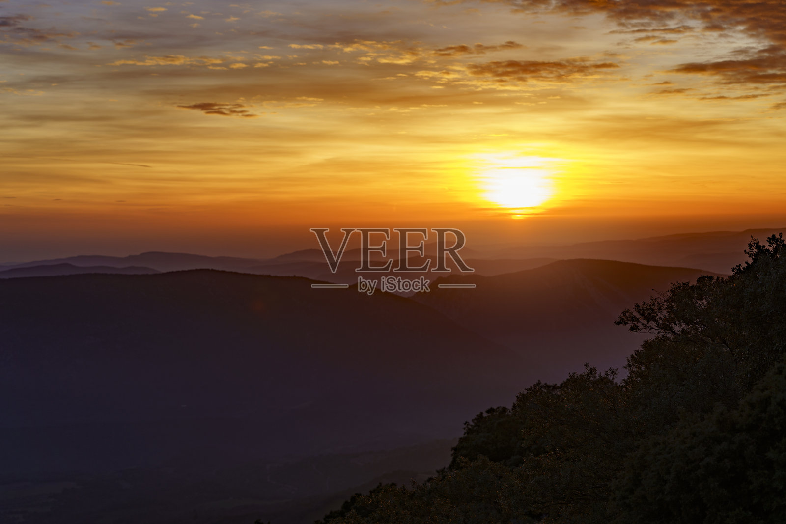 美丽的日落映照在山脉上，周围云彩绚丽多彩。照片摄影图片