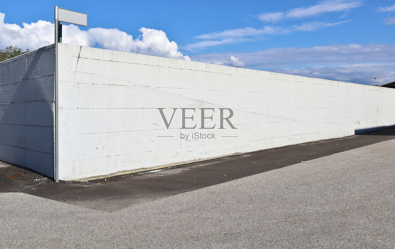 街角的巨大白色混凝土围墙，天空中有蓝天和白云。照片摄影图片