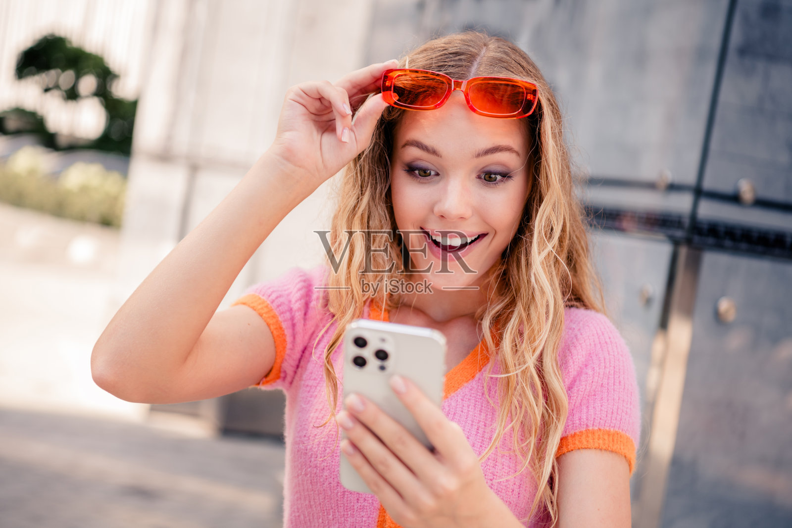 阳光明媚的女孩穿着时尚的衣服，在城市中散步，阅读社交媒体，享受夏季周末的户外时光。照片摄影图片