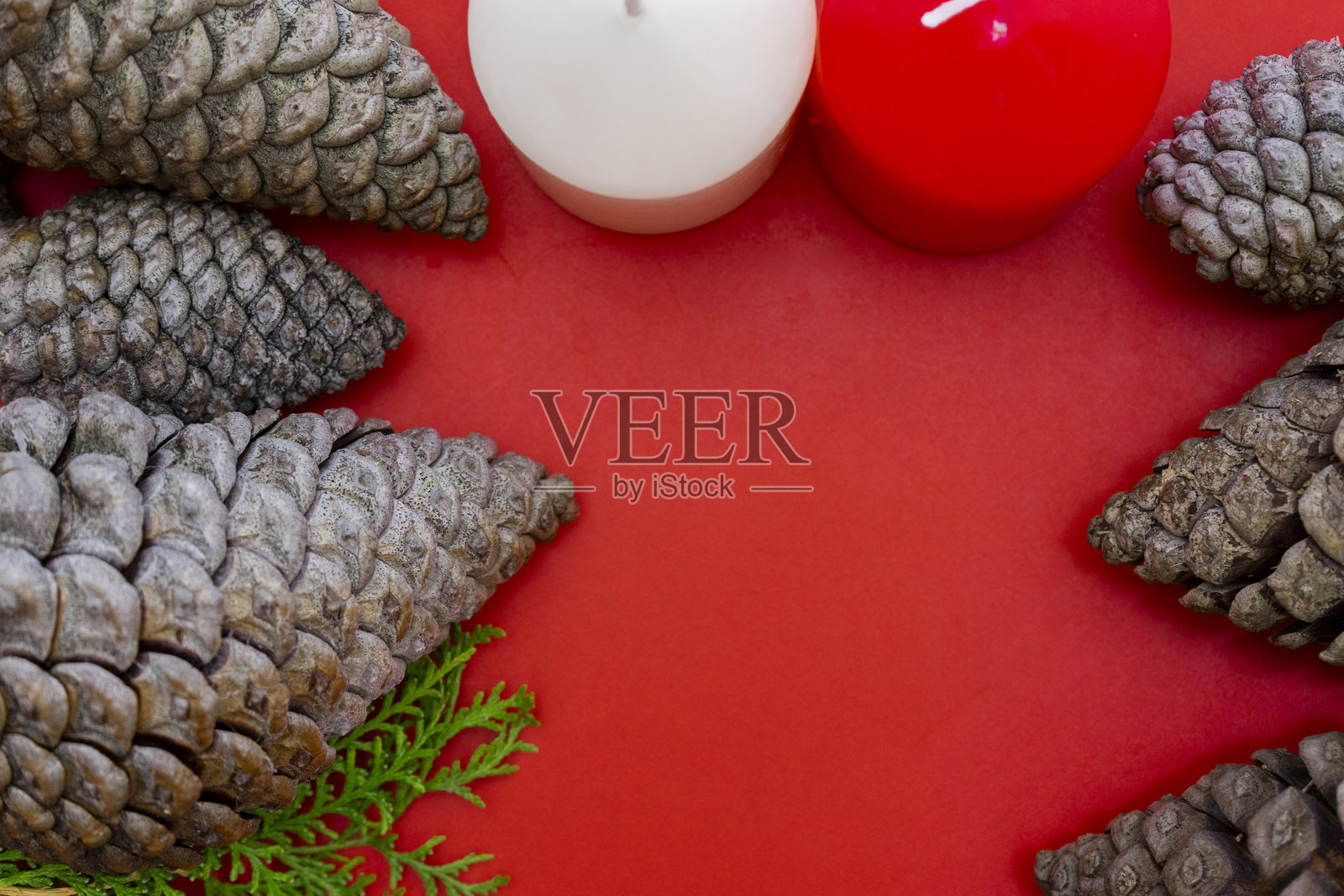 红色背景上的松果和蜡烛圣诞背景。俯视图照片摄影图片