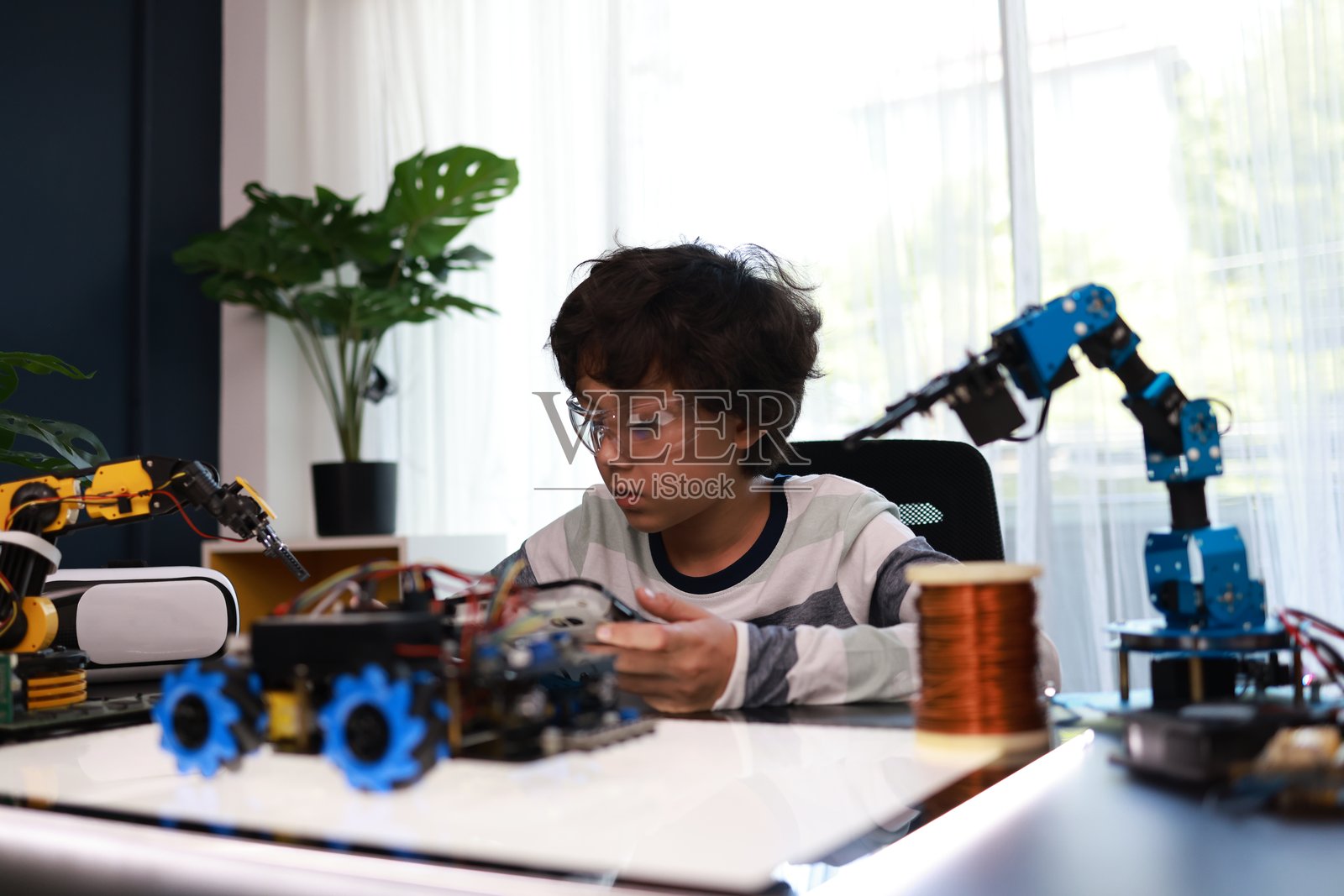 一个年轻的小学生专注于组装和编程机器人汽车。看到这个年龄的孩子能够构建和操作机器人，令人印象深刻。照片摄影图片