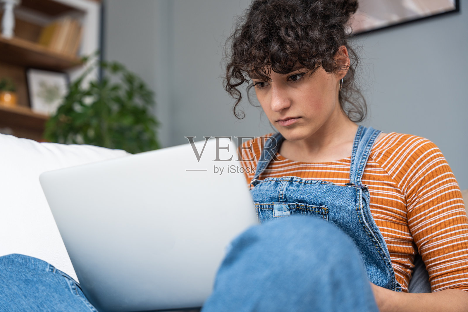 年轻女性或女孩睁大眼睛看着笔记本电脑屏幕，无法相信她的男朋友或未婚夫在网上与她分手。感到压力和困惑的女性面临感情困扰。照片摄影图片