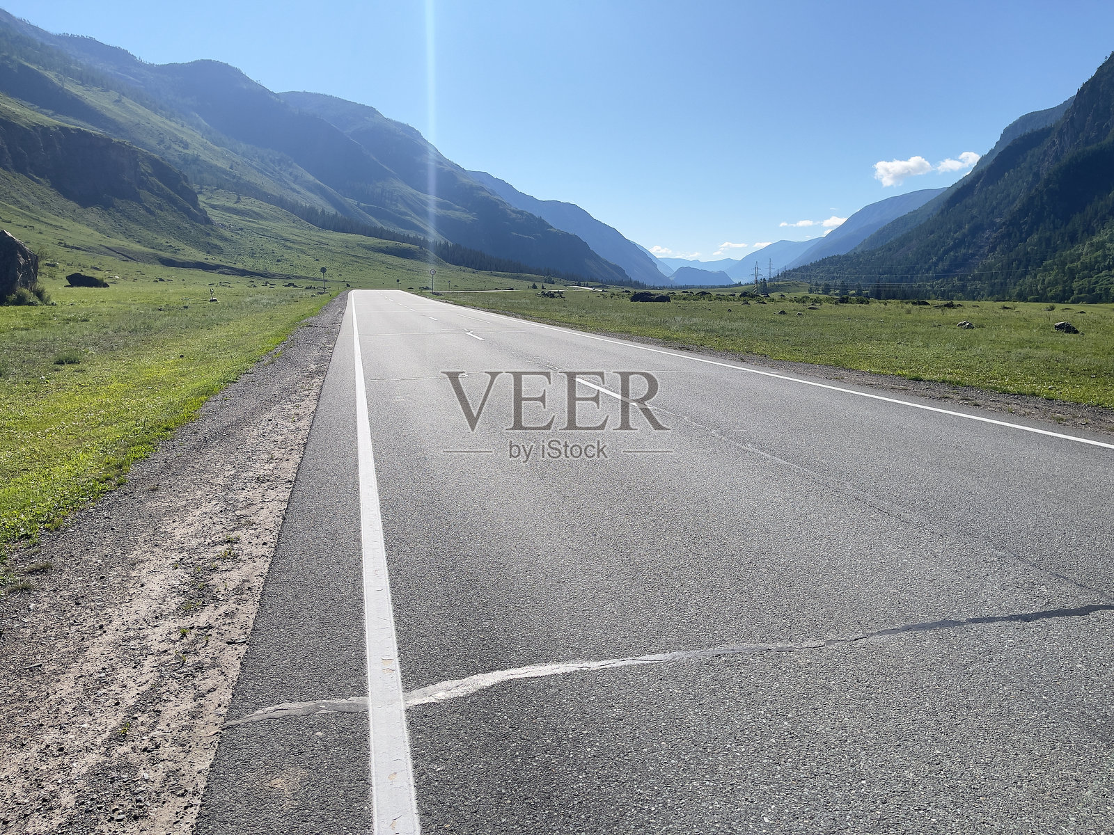 蓝天下的乡村风景，铺有沥青的道路和高耸的山脉照片摄影图片