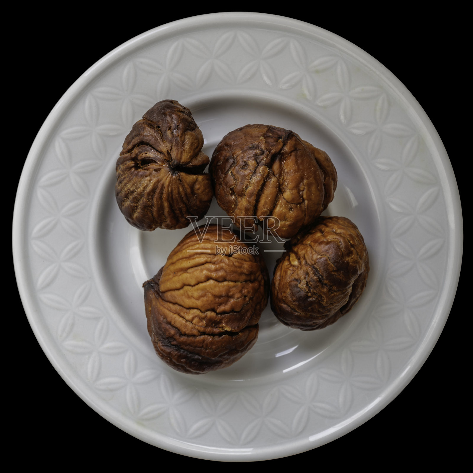 深色背景上的瓷碟与栗子照片摄影图片