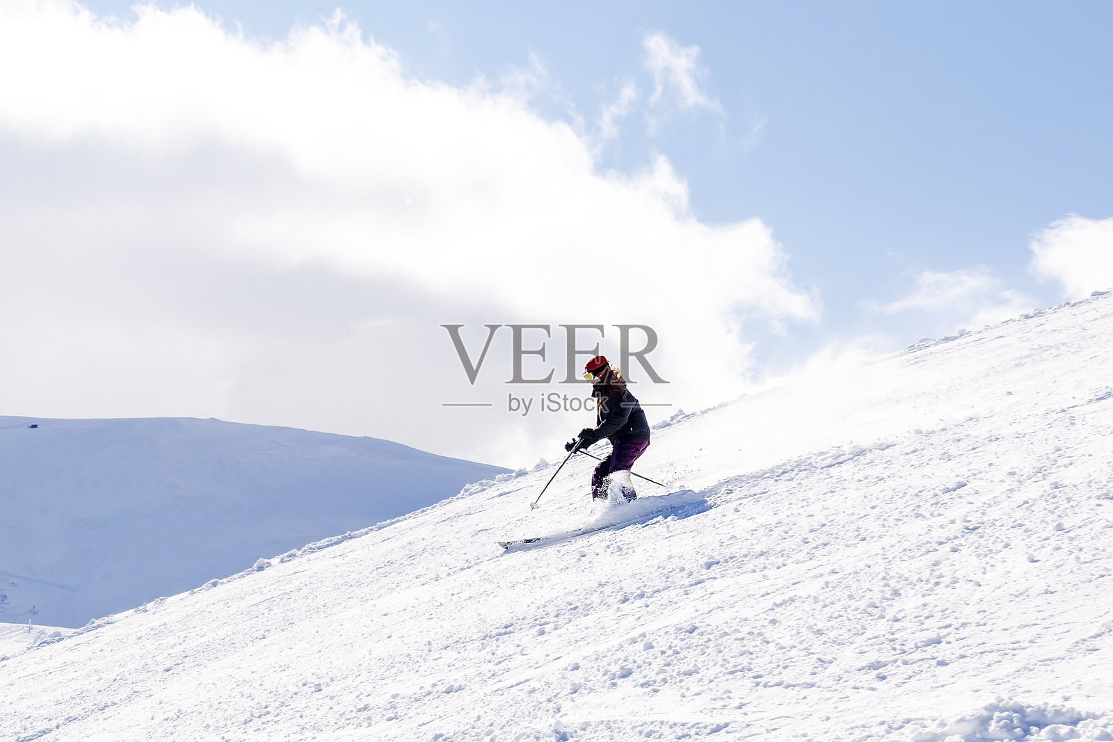 穿着冬季工装的女性在阿尔卑斯滑雪度假村的雪山上滑雪，享受新鲜的粉雪。照片摄影图片