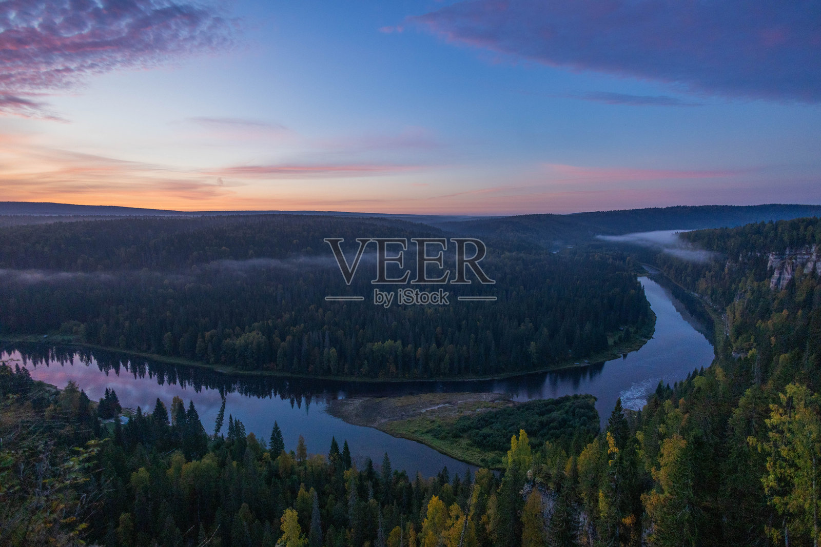 宁静的日出将柔和的色彩洒向天空，照亮了一条蜿蜒的河流，流经郁郁葱葱的森林，营造出宁静的清晨氛围。照片摄影图片