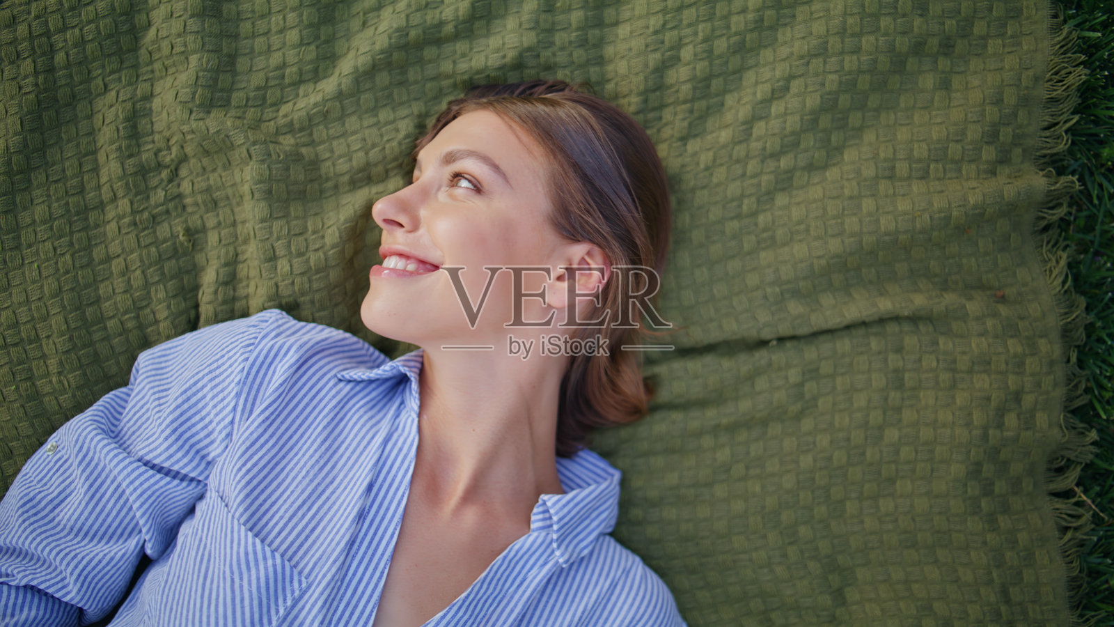 微笑的女士在大自然中躺着，面带愉悦的表情特写。无忧无虑的女性照片摄影图片