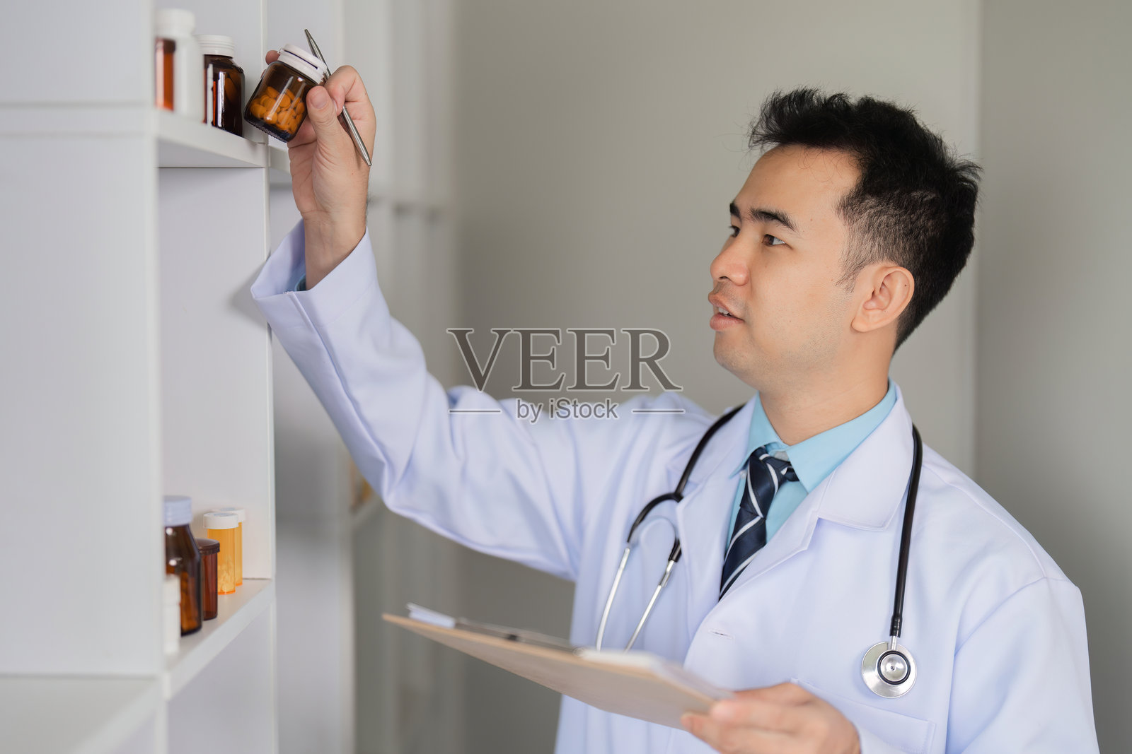 医生在现代医疗设施中检查药物架上的药物，以确保患者安全和护理。照片摄影图片