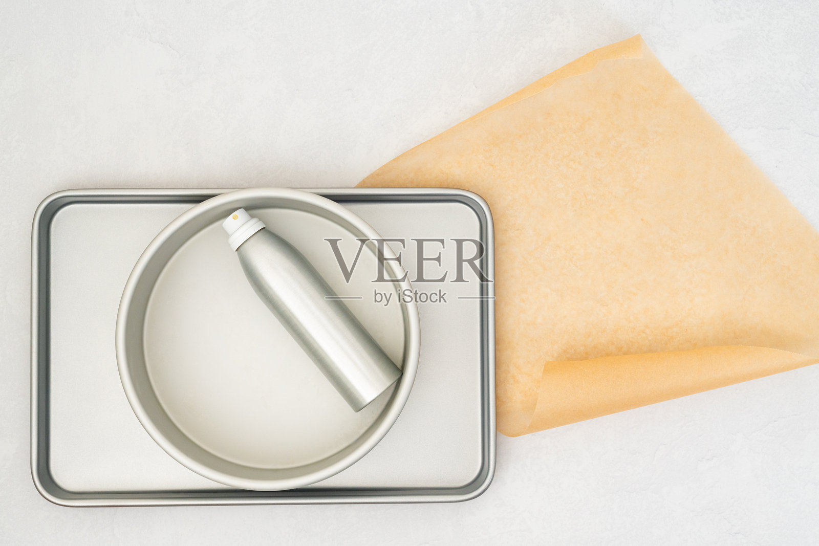 特写平铺构图，展示了铺在烤盘上的羊皮纸，旁边有一瓶油喷雾。照片摄影图片