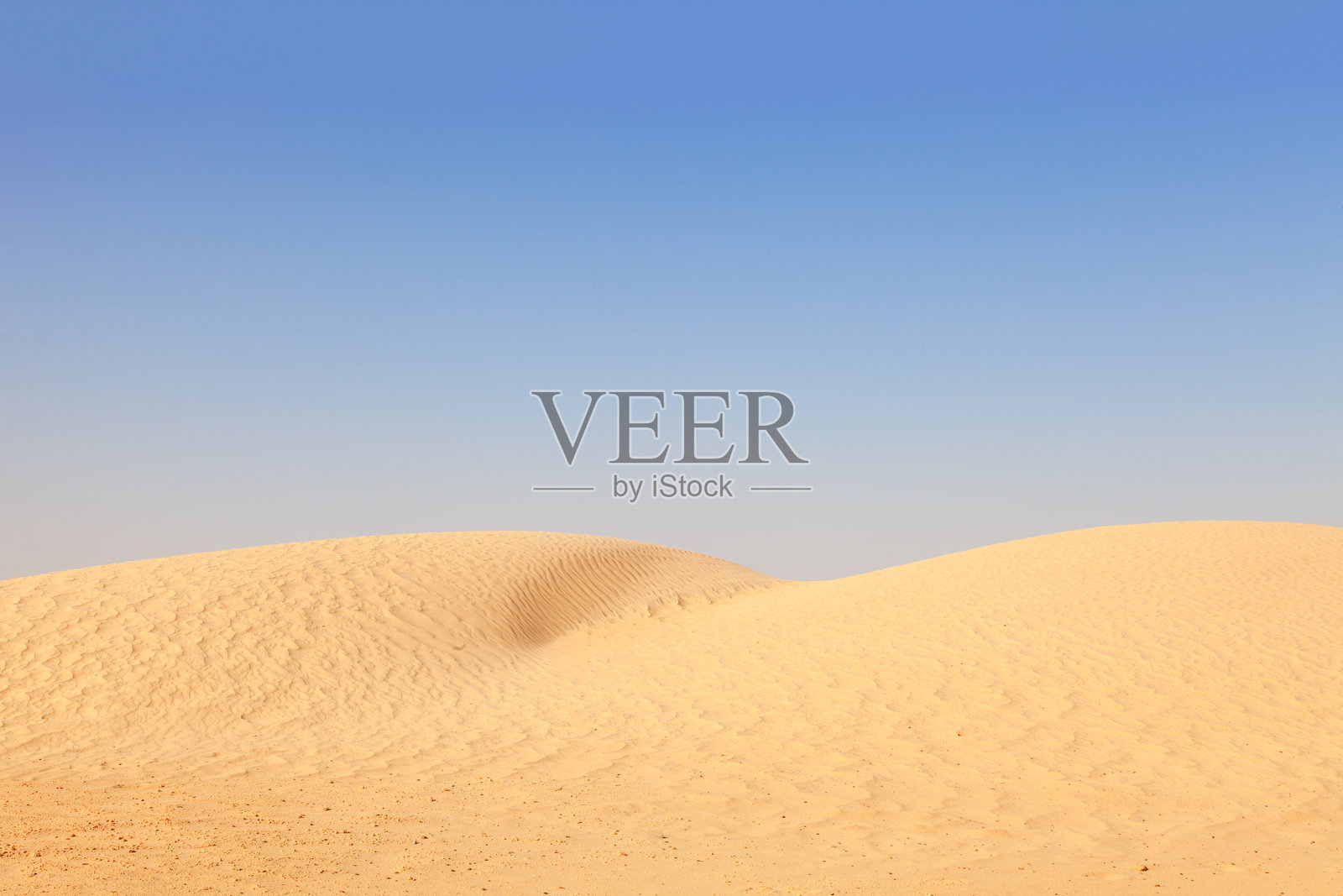 沙漠场景，广袤的沙丘在晴朗的蓝天下延展照片摄影图片