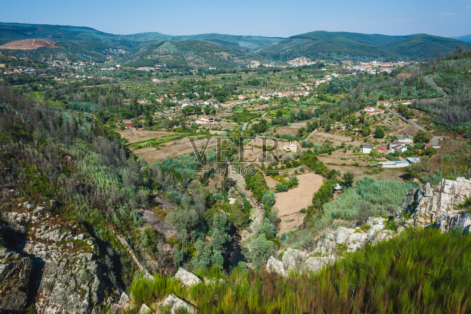 场景展示了一个郁郁葱葱的山谷，散布着田野、乡村房屋和绿色农田。照片摄影图片