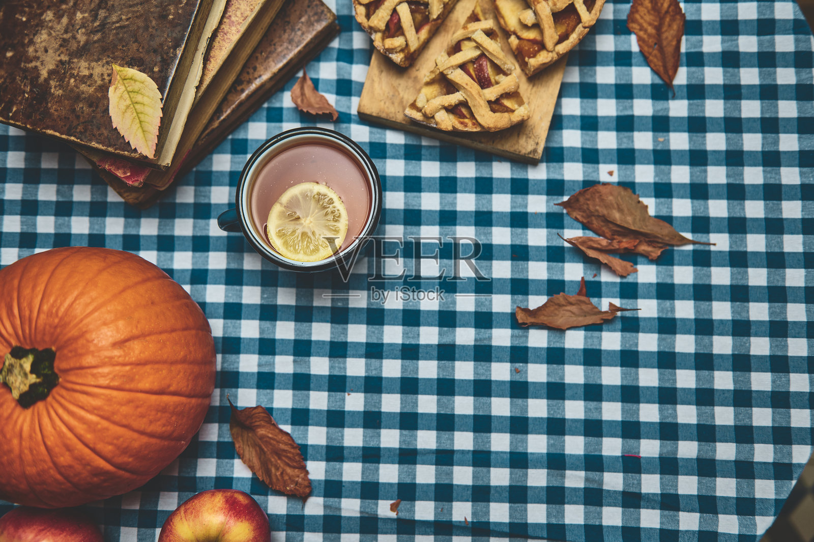 秋季丰收，桌布上摆放着南瓜、苹果派和温暖的饮品照片摄影图片