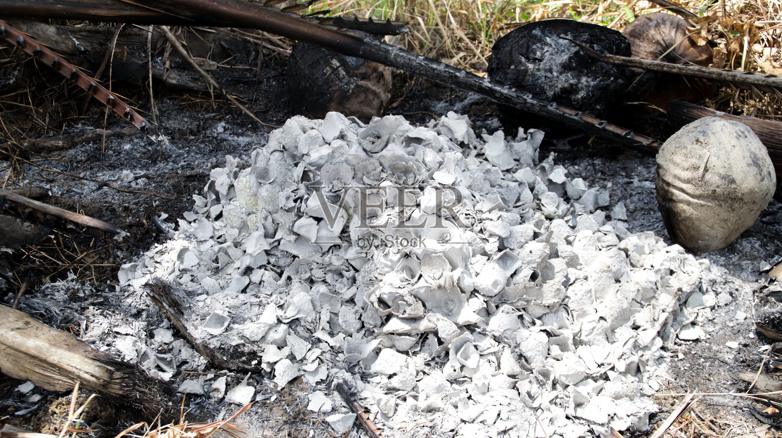 在炎热阳光明媚的日子里，天然户外环境中的烧焦椰子壳灰烬堆照片摄影图片