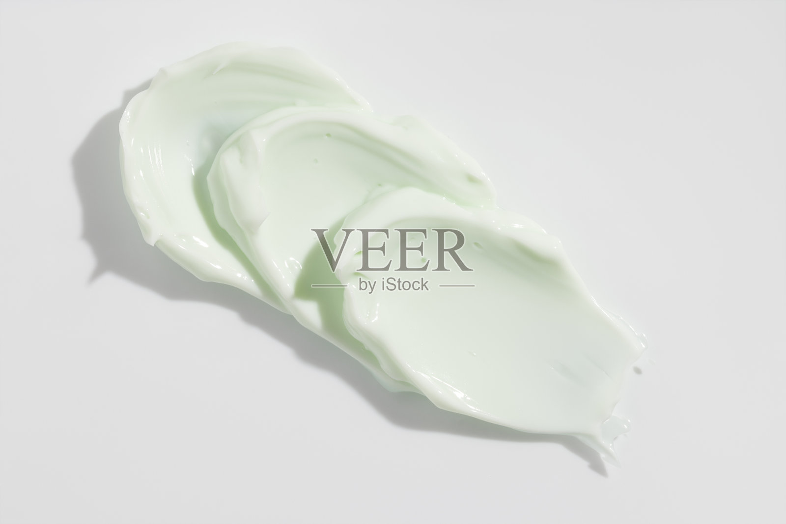 绿色美容霜涂抹在白色背景上。化妆品护肤产品质地。面霜、身体乳液的涂抹样本。照片摄影图片