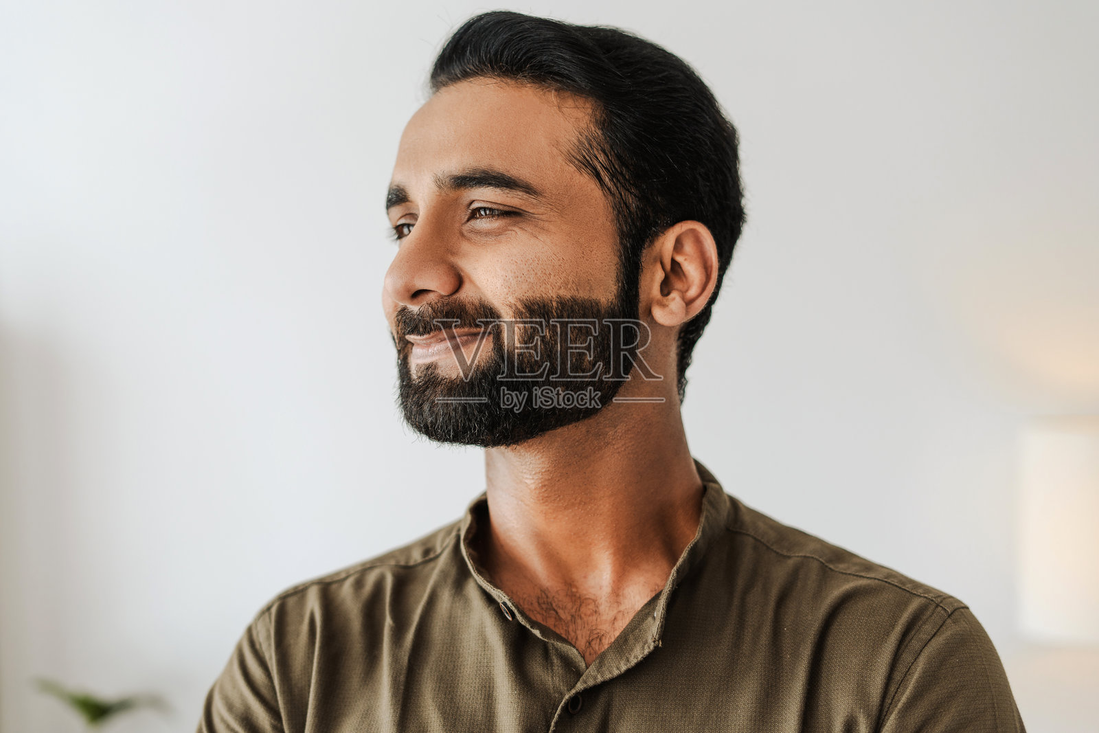 微笑并侧目而视的英俊印度男子特写肖像照片摄影图片