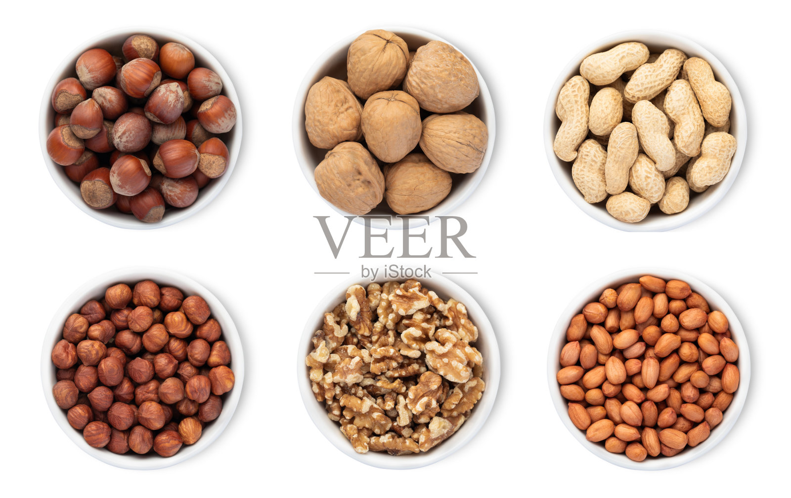 白色背景上孤立的碗盘，盛有榛子、核桃和花生。俯视图。照片摄影图片