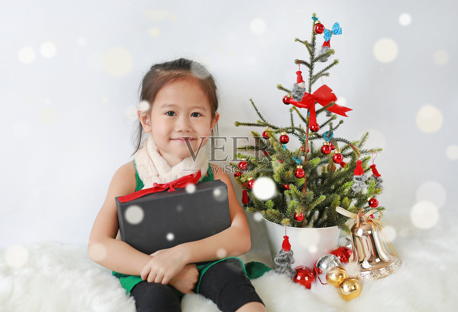 微笑的小亚洲女孩在白色背景上装饰圣诞节，背景有虚化效果。照片摄影图片