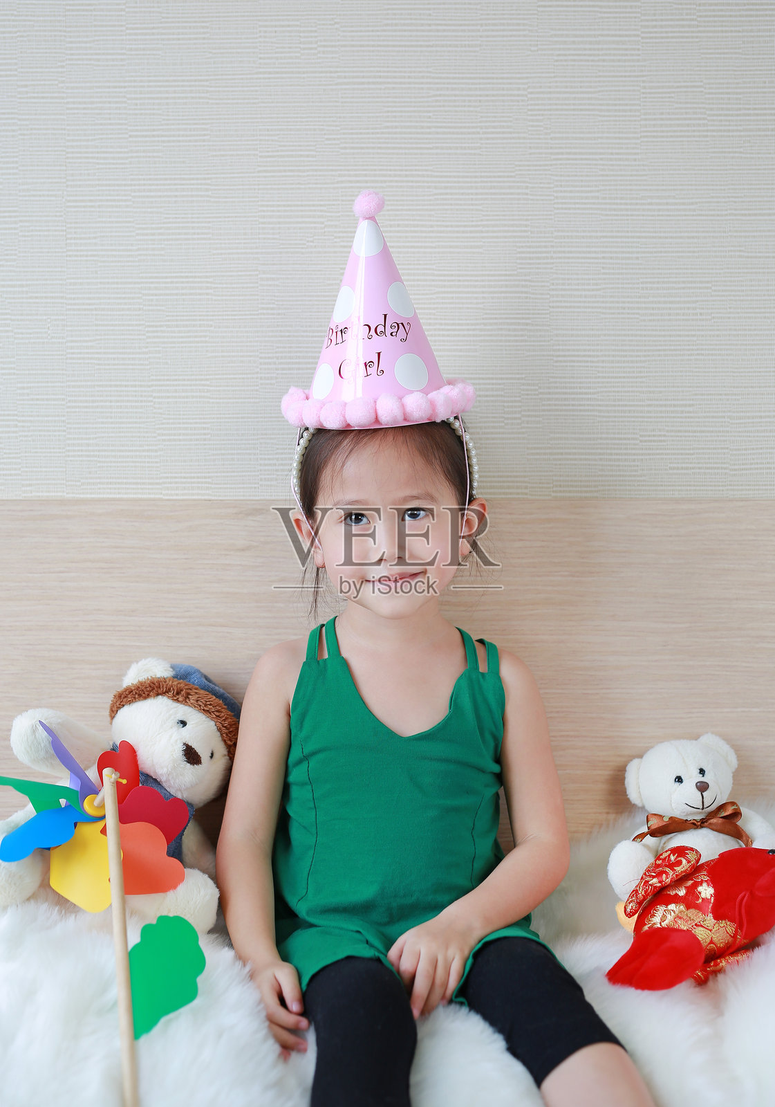 快乐的小女孩与熊和圣诞装饰一起坐在床上。照片摄影图片