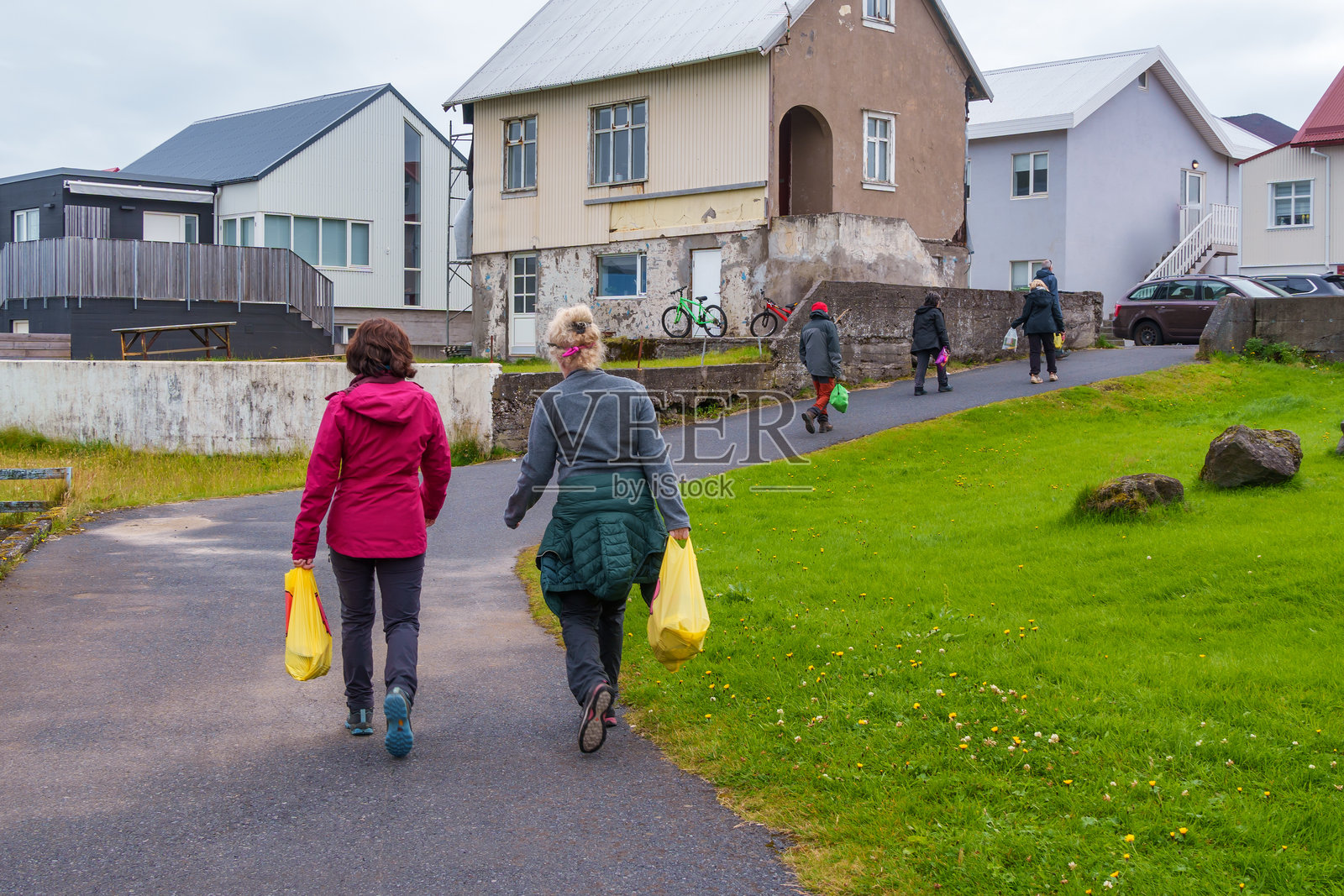 人们在冰岛海马岛的住宅区里提着购物袋散步照片摄影图片