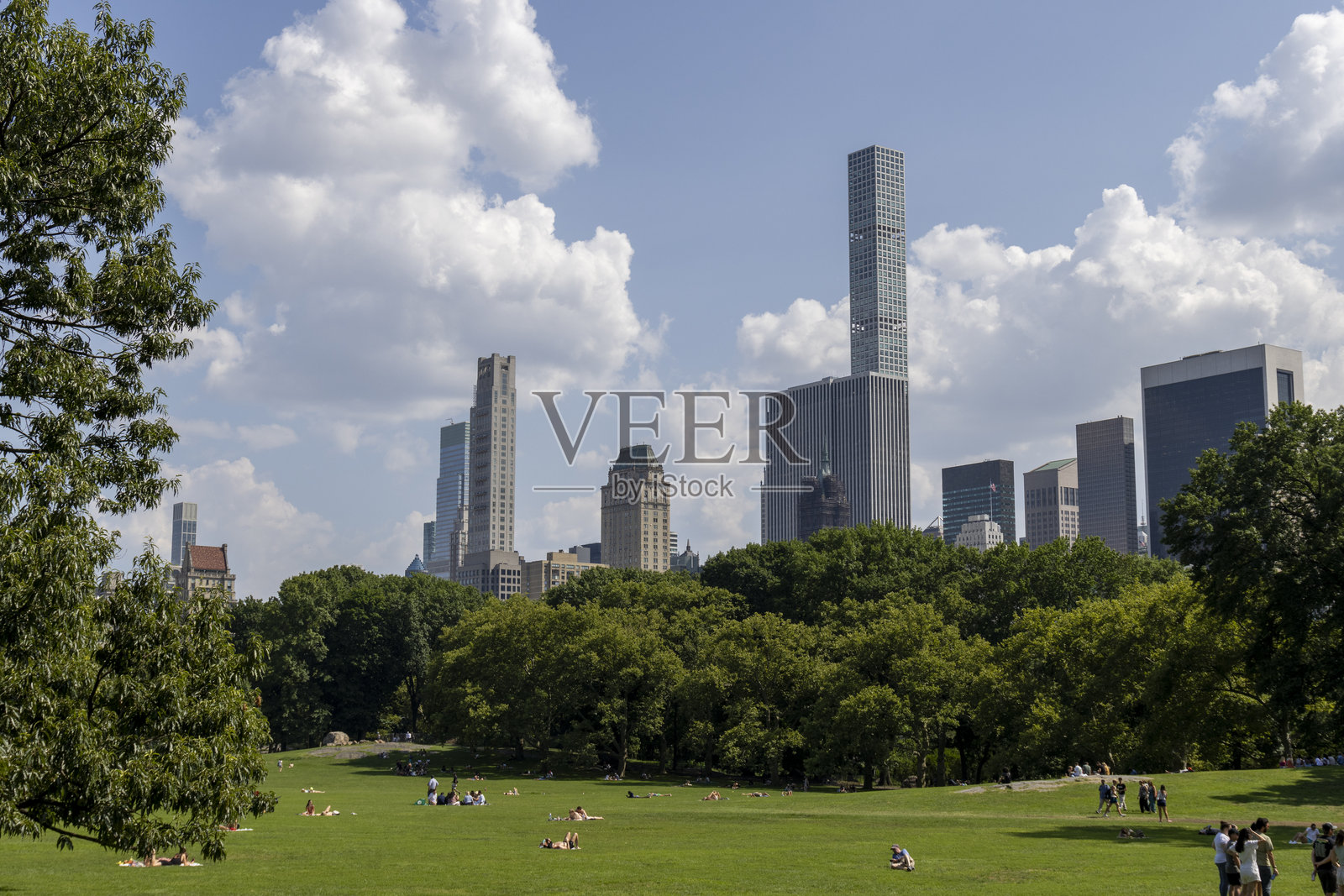 纽约市公园的阳光明媚的一天，背景是摩天大楼，人们在草地上享受户外活动。照片摄影图片
