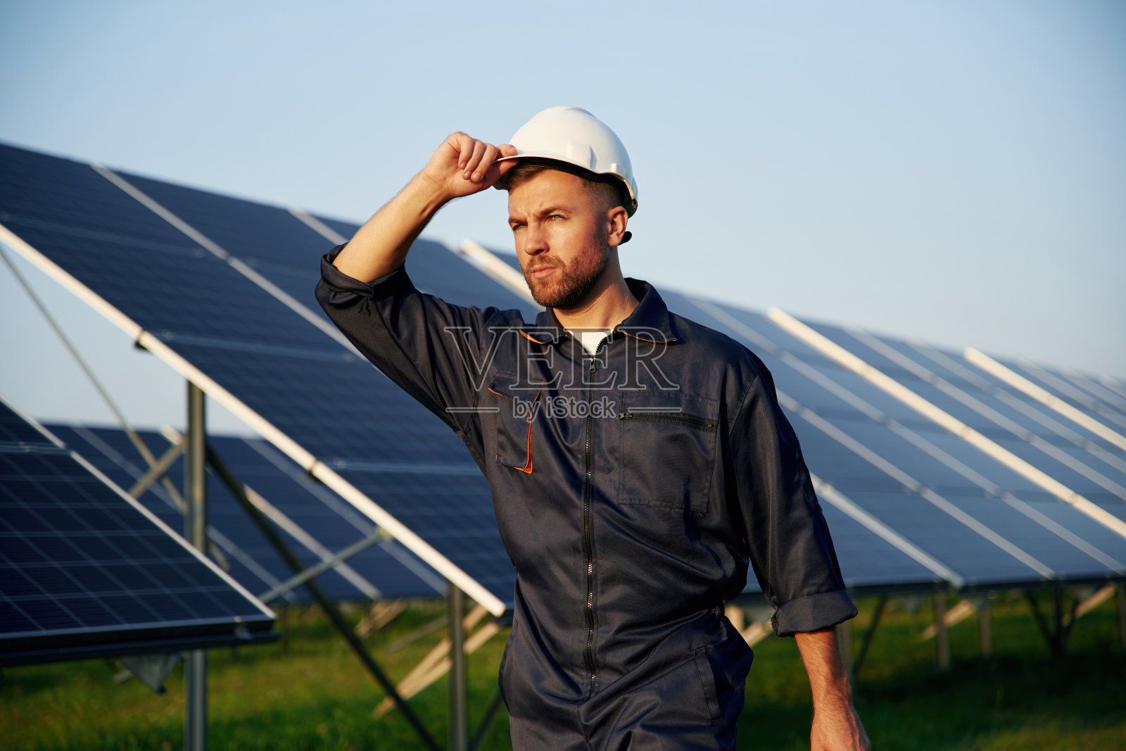 触摸白色安全帽的男人在户外白天与太阳能电池板工作照片摄影图片