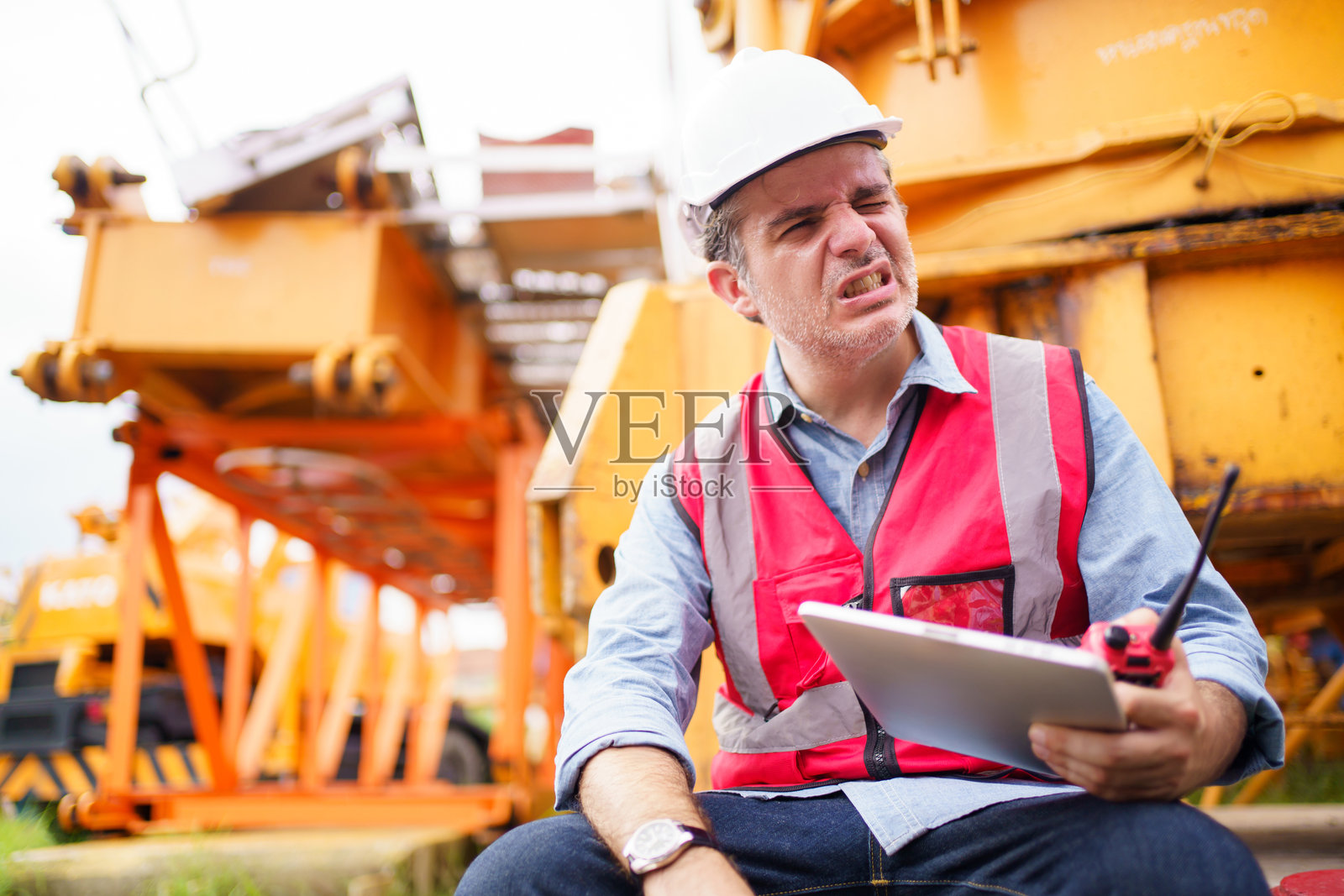 口渴又疲惫的工人坐在地上。照片摄影图片