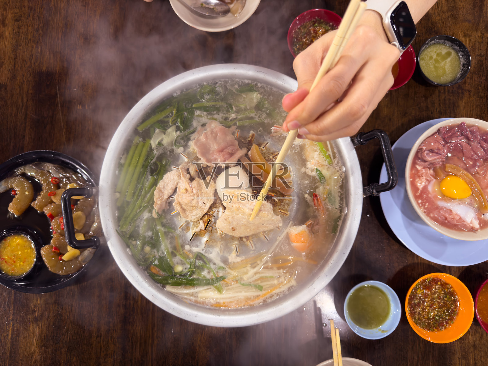 一个无法辨认的女性正在享受吃泰式烧烤（Moo Ka Ta）。照片摄影图片