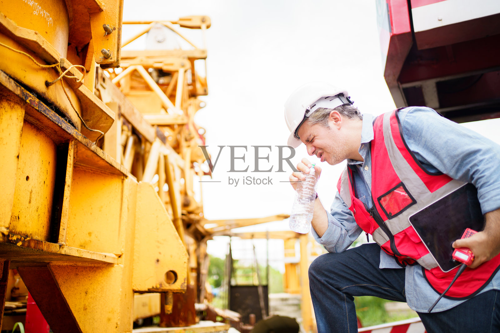 口渴又疲惫的工人坐在地上。照片摄影图片