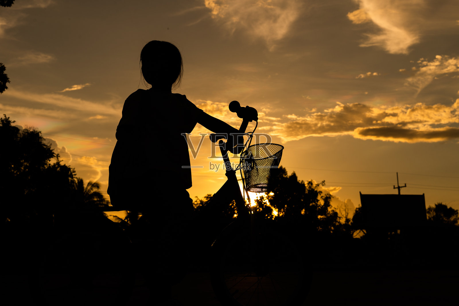 一个女孩骑着前面有篮子的自行车。照片摄影图片