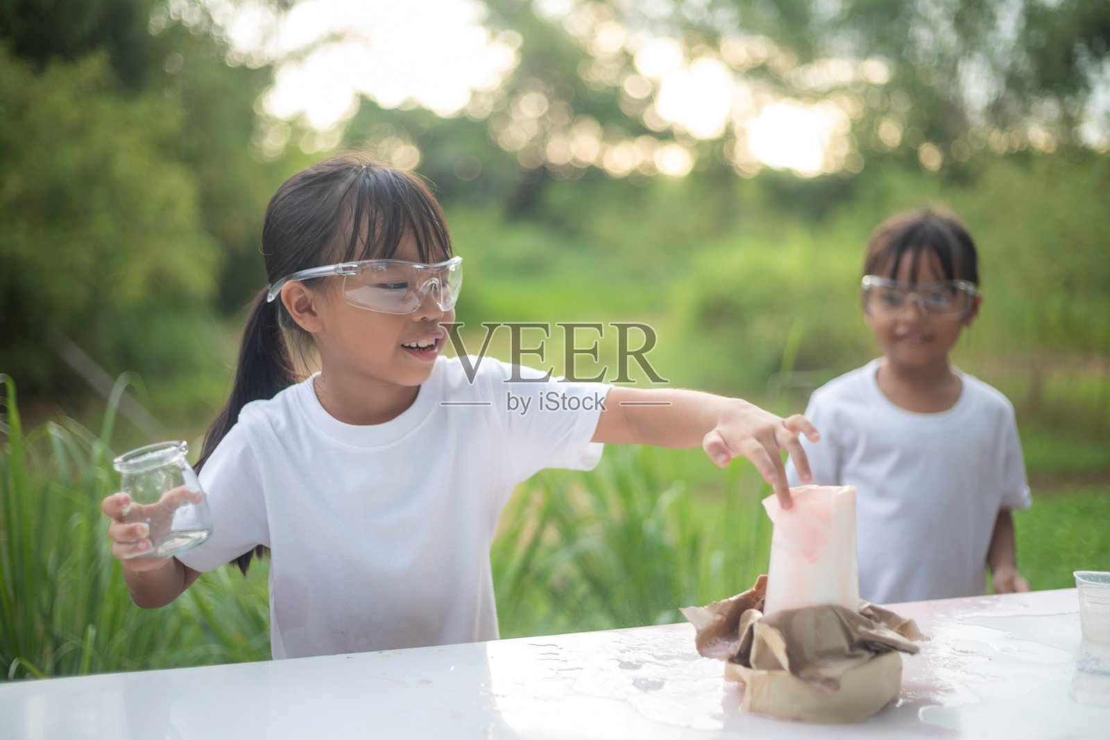 两个小女孩正在玩一个涉及水罐的科学实验照片摄影图片