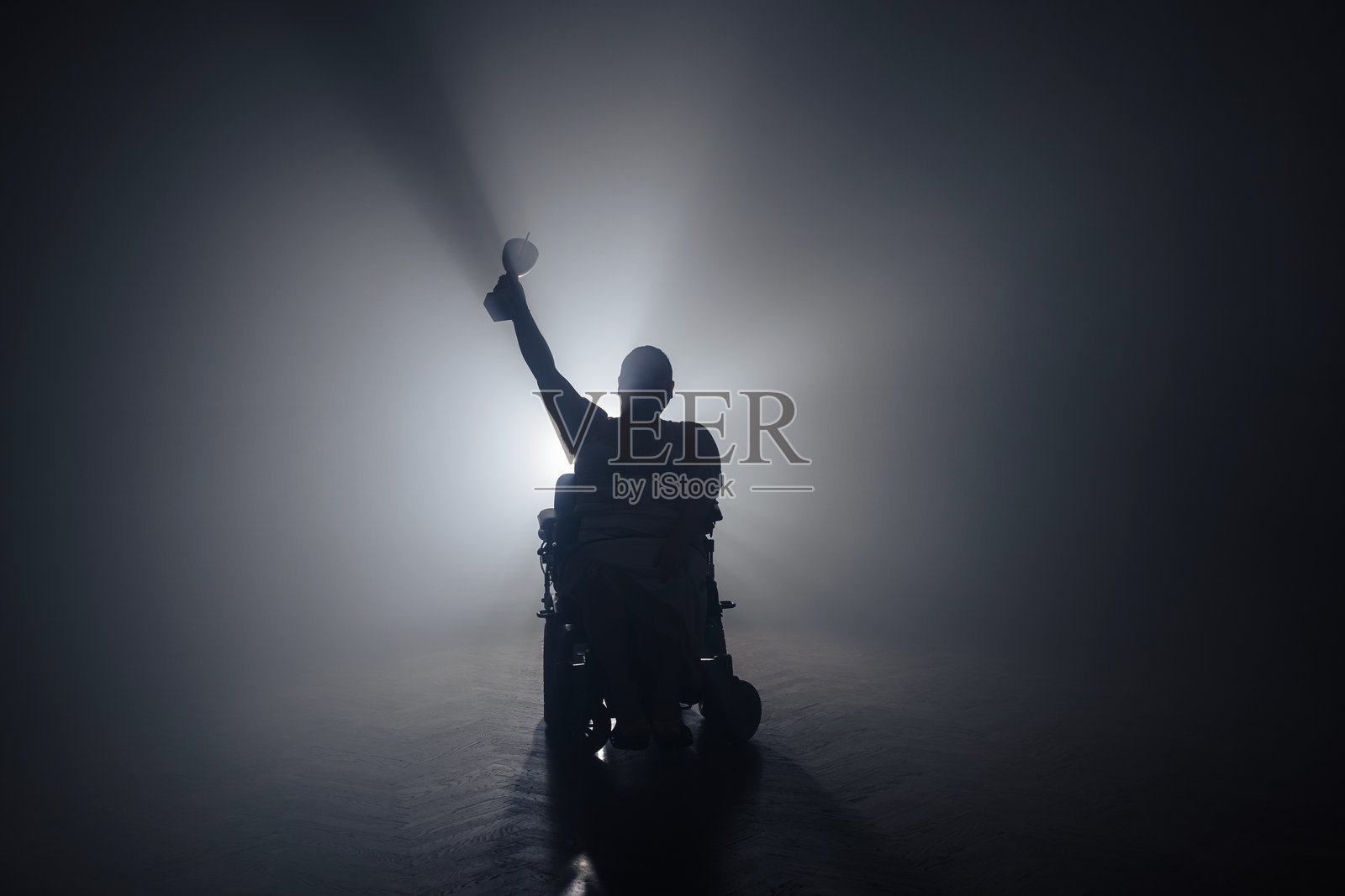 一位身体残疾的女性在昏暗的房间里接受一位男性颁发的胜利奖杯照片摄影图片