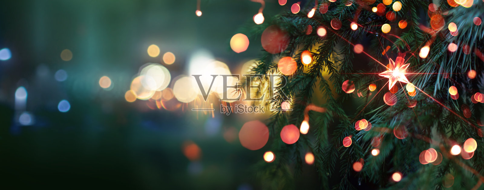 圣诞树上挂着明亮的星星。模糊背景中的城市夜景。照片摄影图片