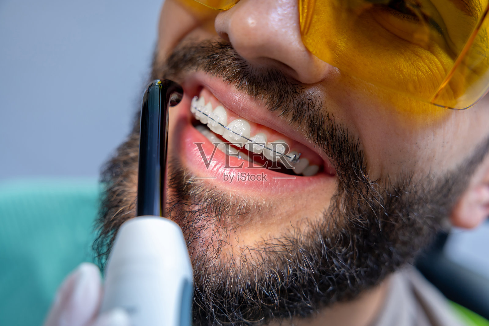 戴着护目镜的男子在牙科椅上接受牙齿护理程序照片摄影图片