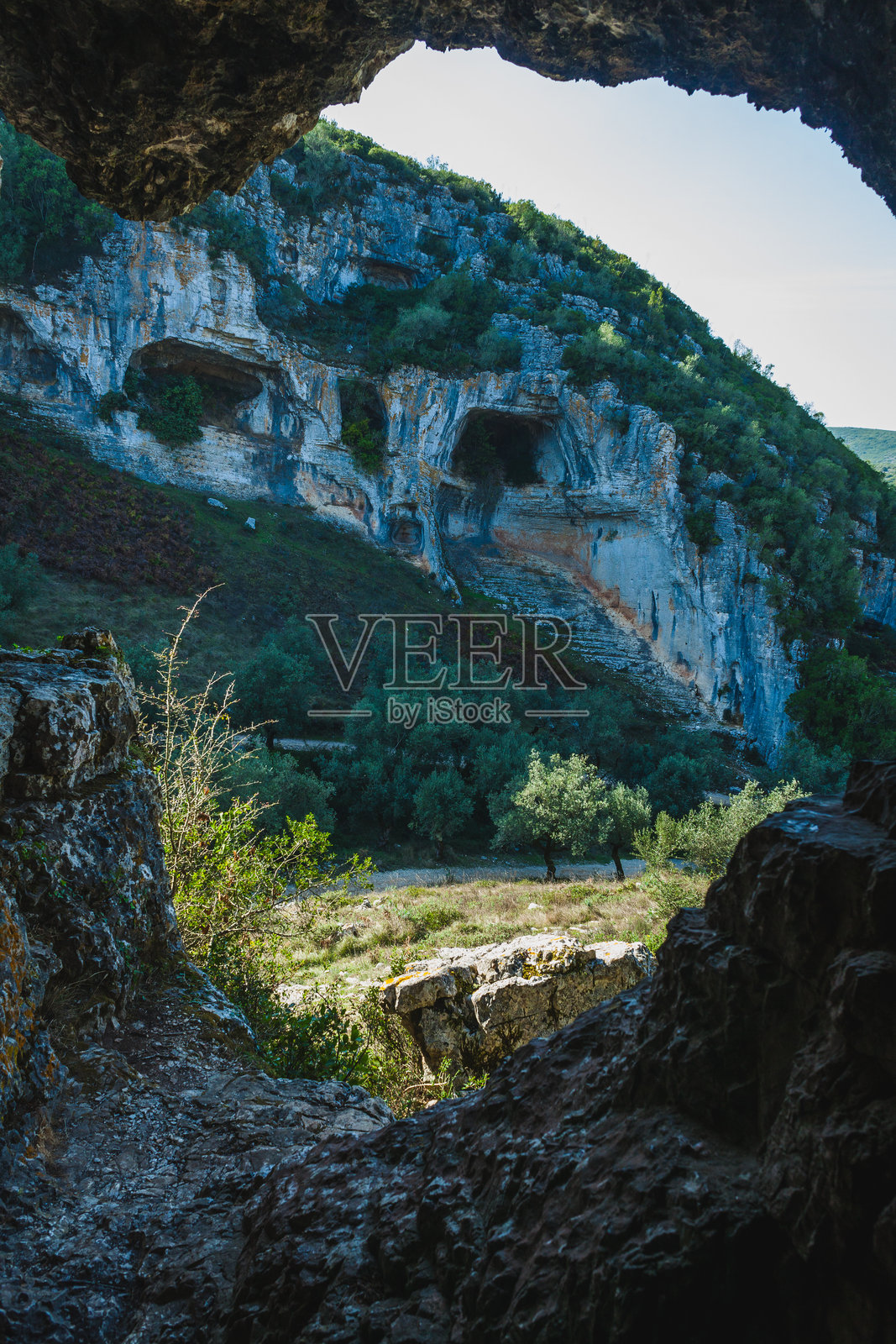 一处戏剧性的石灰岩悬崖，嵌有自然洞穴，可能是葡萄牙卡斯米洛地区的一部分。风化的岩石形成了浅灰色和棕色的混合色调。照片摄影图片