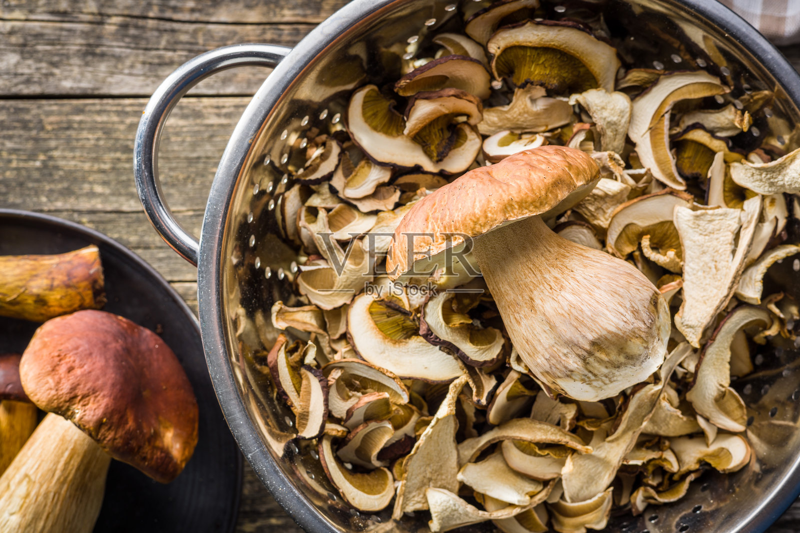 干香菇。切片的牛肝菌放在木桌上的漏网中。照片摄影图片