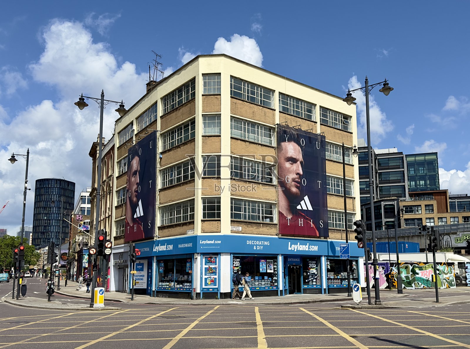 在伦敦肖尔迪奇,一栋商业办公楼的侧面悬挂着大型广告海报,宣传阿迪达斯,位于一家DIY商店的上方。照片摄影图片