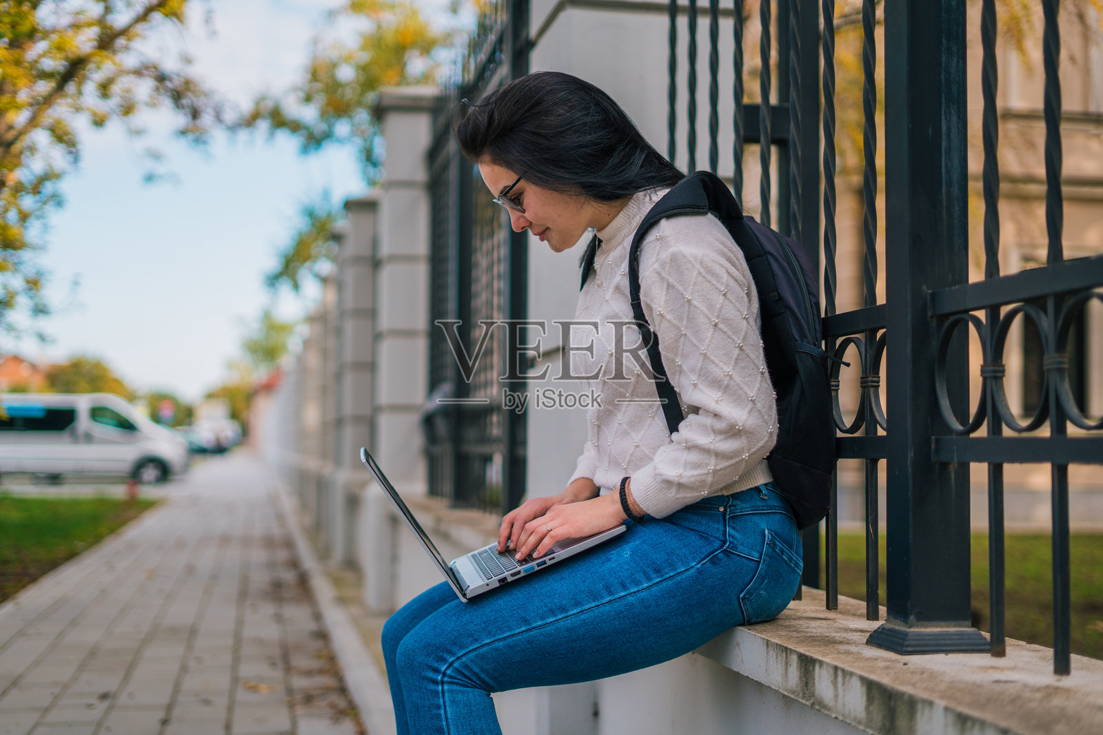 一名女学生坐在教职员工面前，背着书包，面前放着笔记本电脑。照片摄影图片