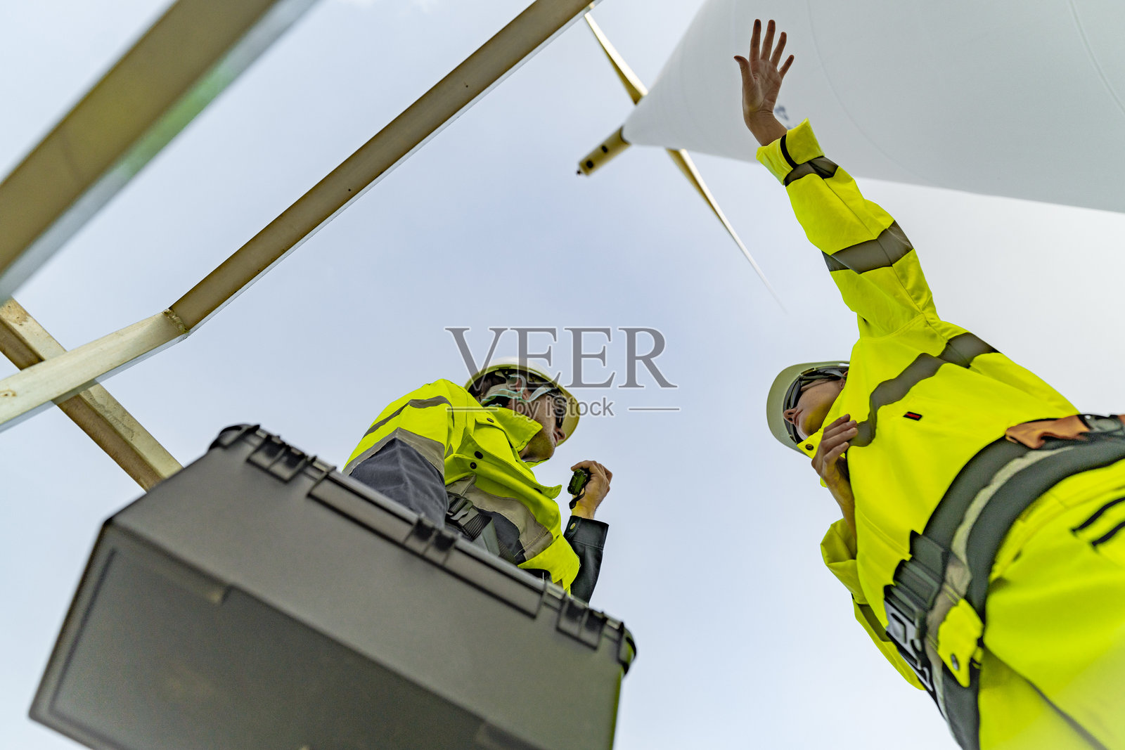 一组工程师在风电场完成风力涡轮机维护后庆祝成功。可再生能源团队合作、绿色能源和可持续能源实践的体现。照片摄影图片