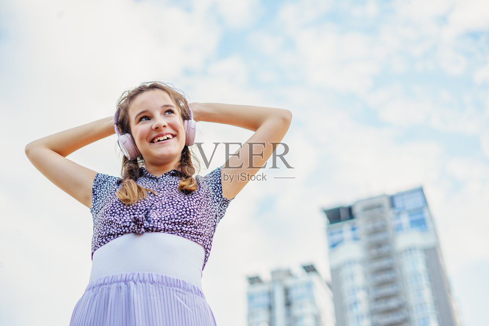 可爱快乐的女孩在夏季城市街道上听音乐跳舞照片摄影图片
