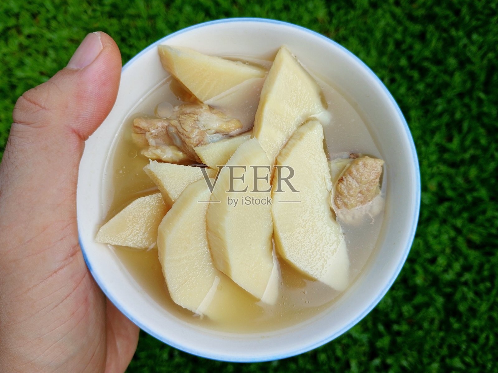 碗里的竹笋排骨汤 - 绿色背景。照片摄影图片