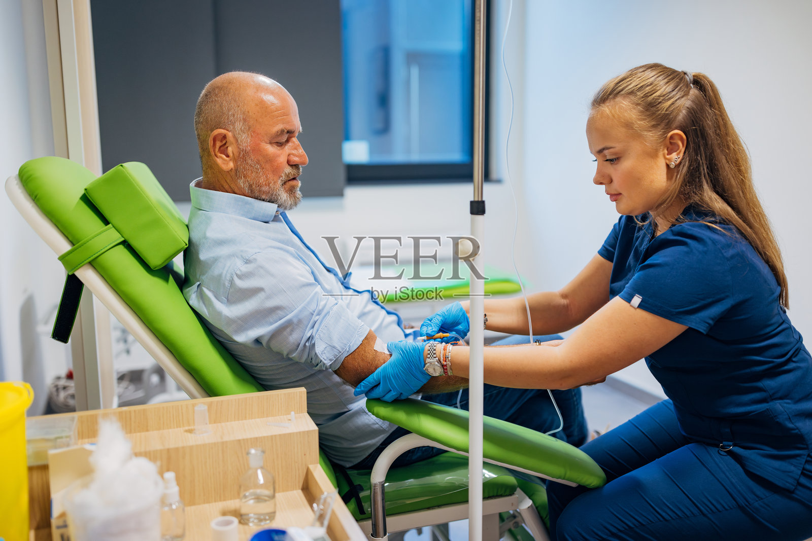 女实验室技术员用针头刺穿病人的手臂静脉以收集血液到试管中照片摄影图片