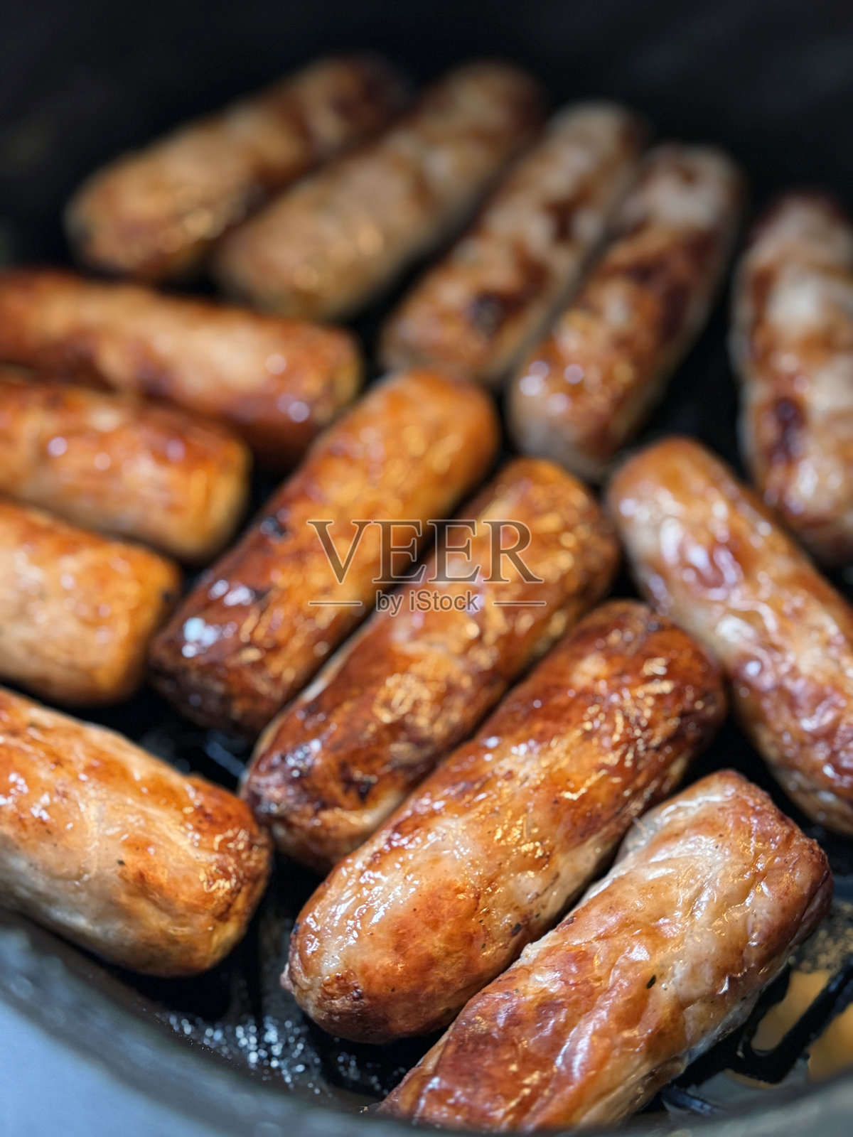 全景图，空气炸锅中煮熟的棕色猪肉香肠，健康的煎锅替代选择，俯视角度。照片摄影图片