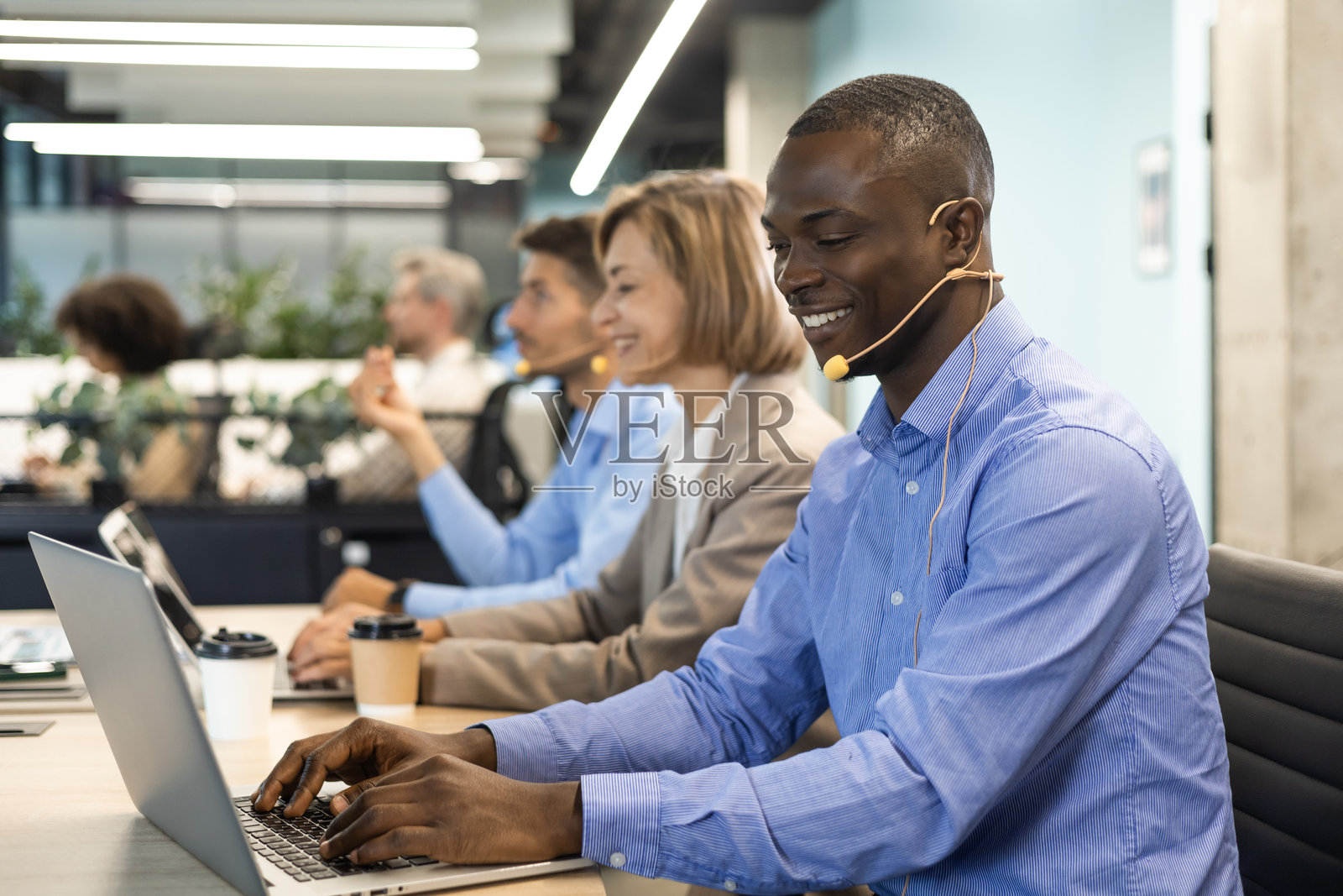 快乐的年轻男性客服专员在办公室工作。照片摄影图片